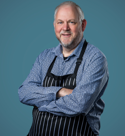 Paul in chef apron with arms folded